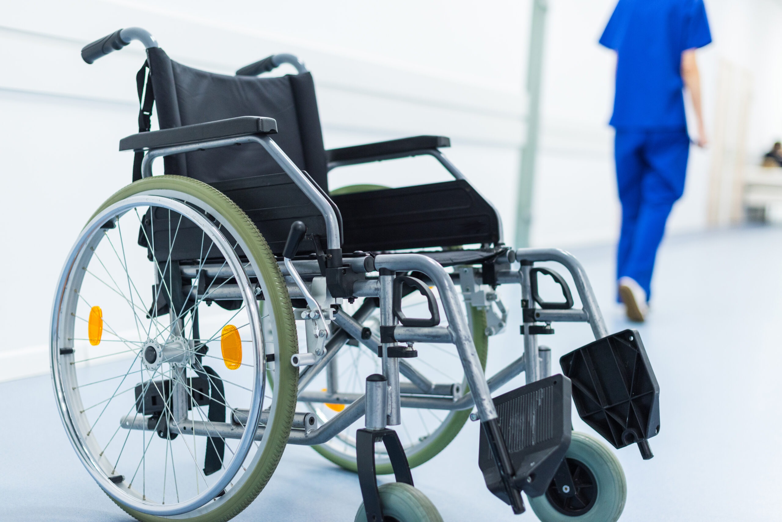 female surgeon in hospital corridor, wheelchair on foreground